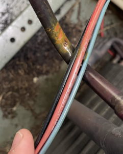 Close-up of electrical wires and a rusty pipe, likely from an HVAC unit, being inspected by Mission HVAC in Huntsville, AL.