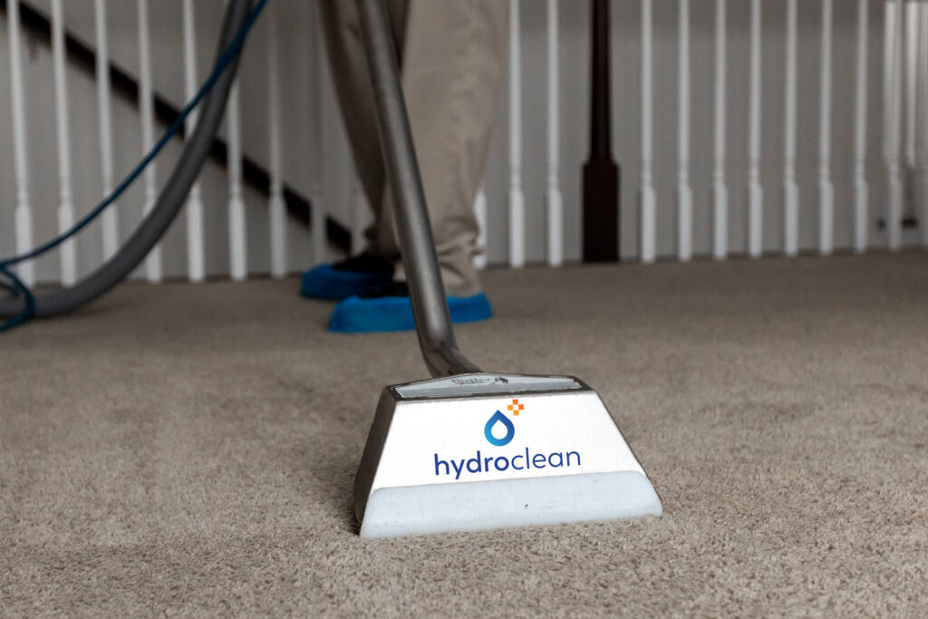 A close-up of a professional carpet cleaning wand with the Hydro Clean logo on a residential carpet in Baltimore, MD.