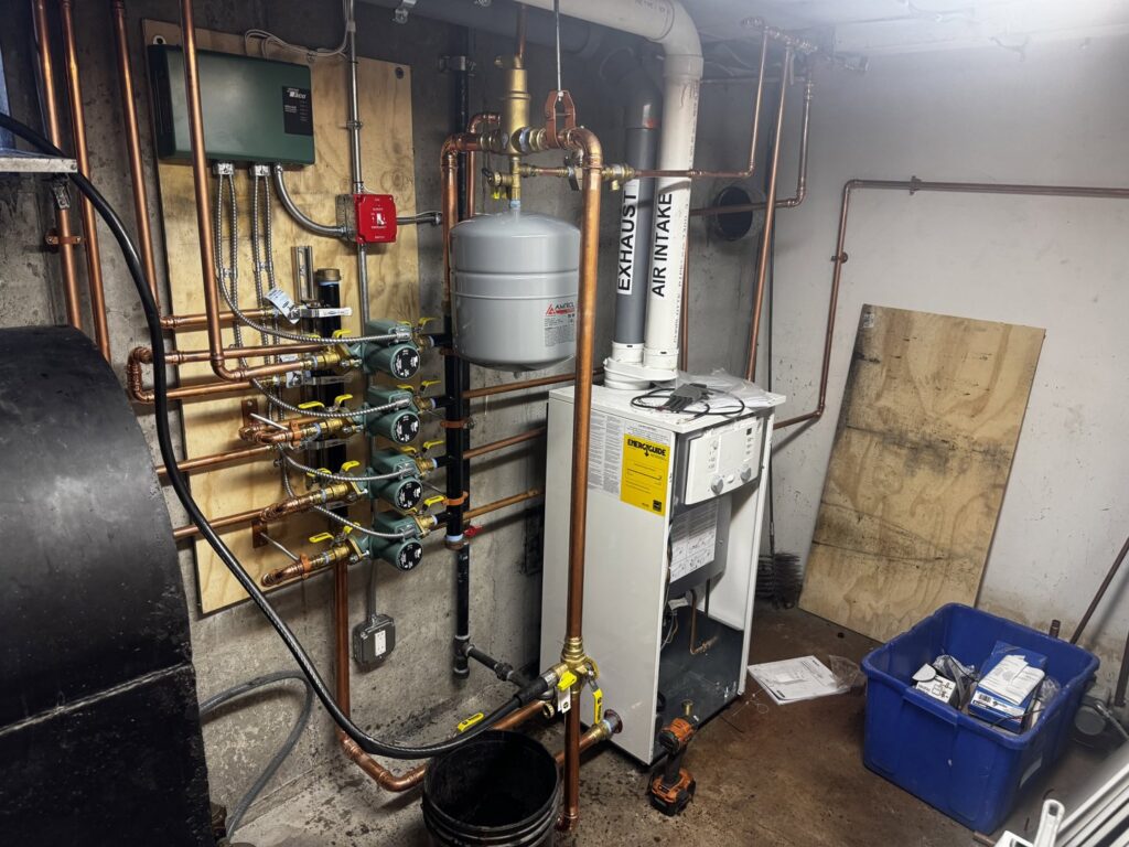 A comprehensive hydronic heating boiler system with copper pipes and expansion tank installed by PureTemp Heating and Cooling in Salem, NH.