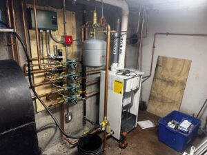 A comprehensive hydronic heating boiler system with copper pipes and expansion tank installed by PureTemp Heating and Cooling in Salem, NH.