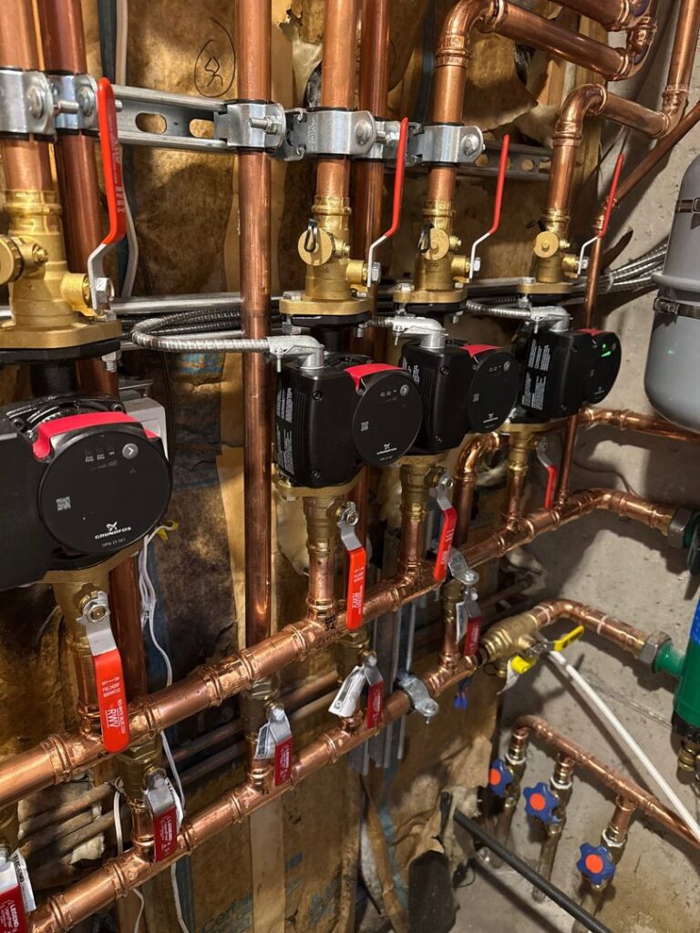 A complex hydronic heating manifold system with copper pipes and pumps, installed by Authority Heating & Cooling in Orem, UT.