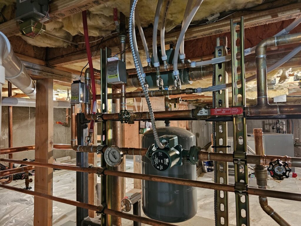 Intricate copper piping, valves, and pumps of a hydronic heating system installed by Perfect Temp LLC in Bozeman, MT.