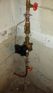 Vertical copper piping with a pump and valves, part of a hydronic heating system by David J. Winston Co. in Erie, PA.