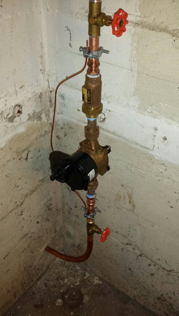 Vertical copper piping with a pump and valves, part of a hydronic heating system by David J. Winston Co. in Erie, PA.