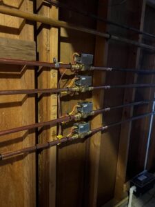 A hydronic heating or zone control system with copper pipes and valves installed by Neal Harris Service Experts in Overland Park, KS.