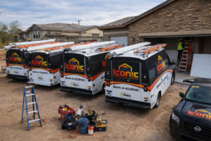 Iconic Garage Door Service vans and truck at a job site with a technician installing a garage door in Queen Creek, AZ