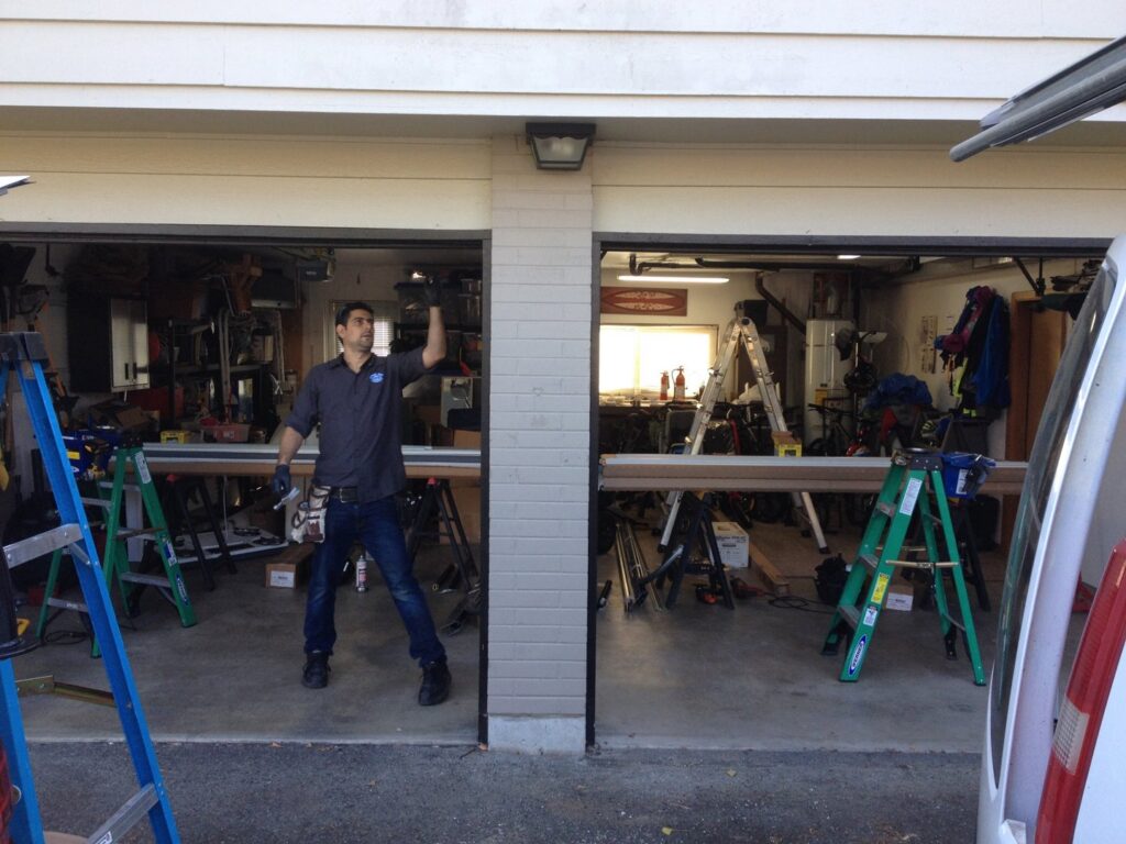 An IGD Garage Door Repair technician standing inside a garage, surrounded by tools and equipment, ready to perform a service in Renton, WA.