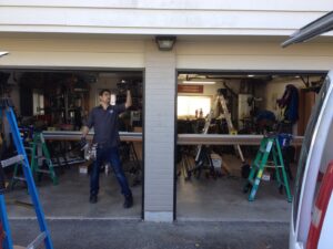 An IGD Garage Door Repair technician standing inside a garage, surrounded by tools and equipment, ready to perform a service in Renton, WA.