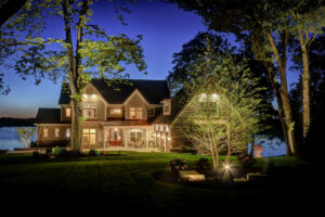 A beautifully illuminated house at night with a manicured lawn and landscape lighting by Miguel Landscaping LLC in Janesville, WI.
