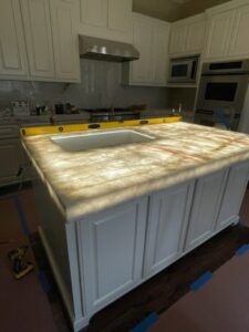 A kitchen island with a beautifully illuminated countertop, showcasing specialty lighting installation by LOJ Electric, LLC in Houston, TX.