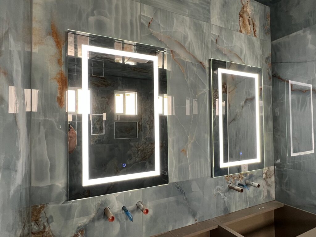 Illuminated mirrors being installed in a bathroom by Gilmore Electrical in Saint Louis, MO