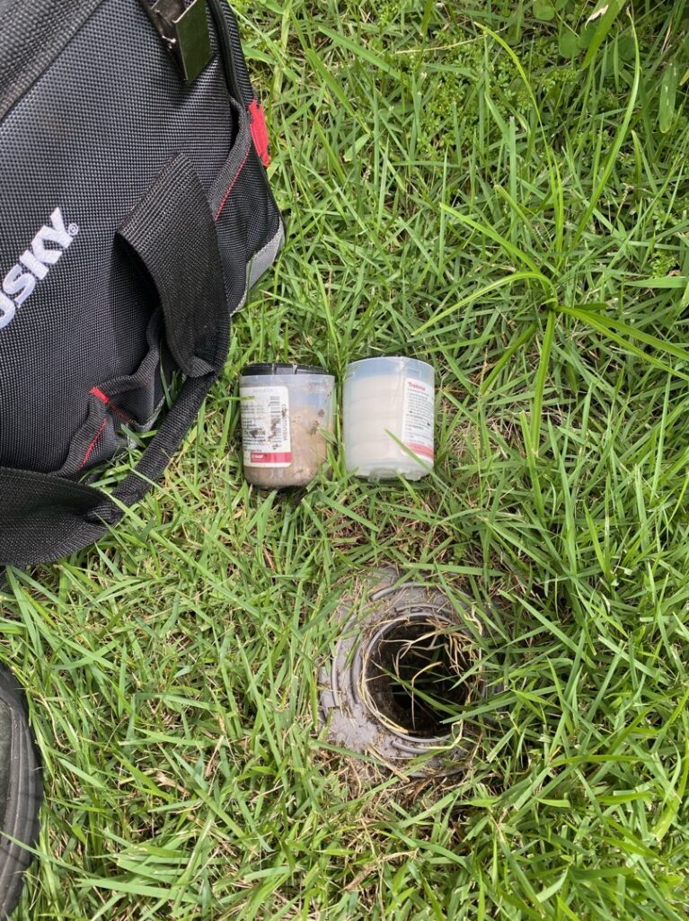 Two pest bait stations placed near an in-ground access point by Crawford Pest Control in Jacksonville, FL.