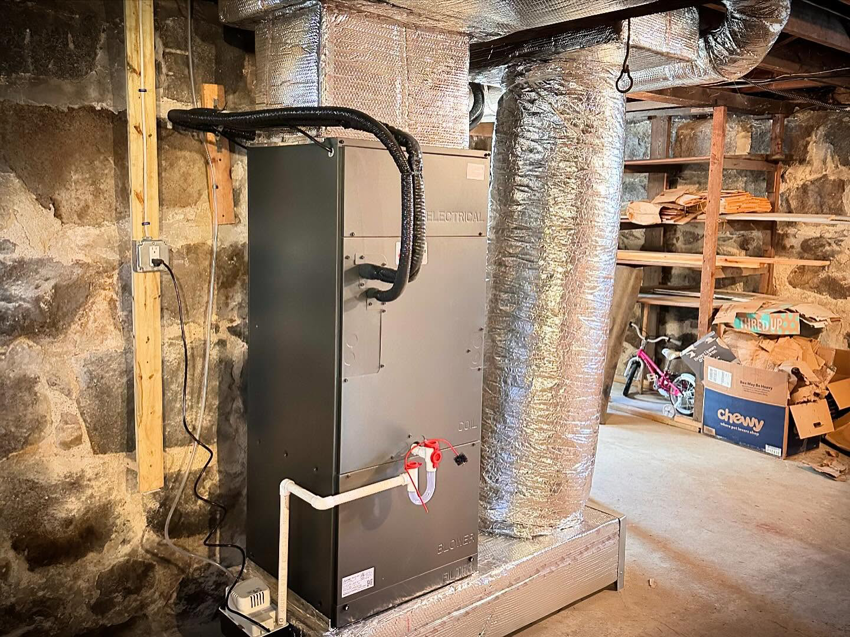 An indoor air handler and insulated ductwork installed in a basement by ComfortCool Mass in Quincy, MA