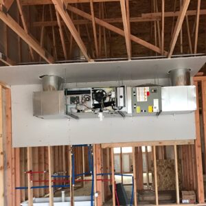 An indoor air handler unit with ductwork connections installed in a ceiling during construction by Semenik Hvac/r in Spokane, WA.
