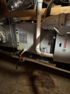 An indoor air handler or furnace unit with ductwork and condensate lines installed in an attic by Desert Heroes HVAC in Phoenix, AZ