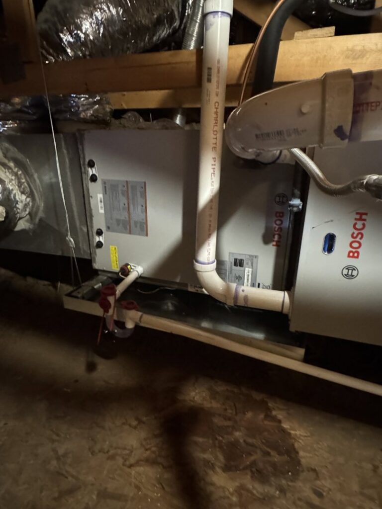 An indoor air handler or furnace unit with ductwork and condensate lines installed in an attic by Desert Heroes HVAC in Phoenix, AZ