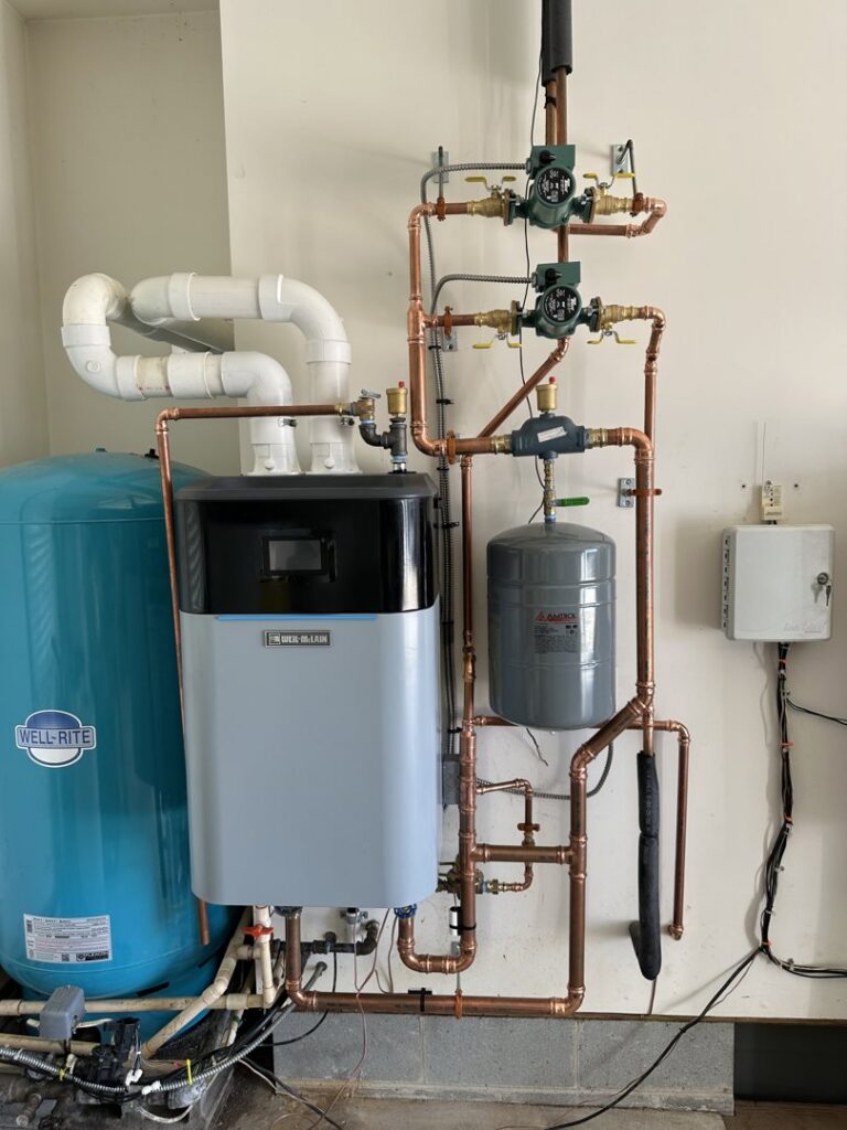 A professionally installed indoor boiler and water heater system with copper piping by McTeer's Heating & Cooling in Salisbury, MD.