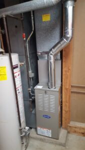 An indoor Carrier furnace and ductwork installed in a utility room by Custom Climates in Iowa City, IA.