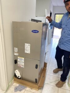 A technician installing or servicing an indoor Carrier HVAC air handler unit for BV Air Conditioning & Heating in Dallas, TX.