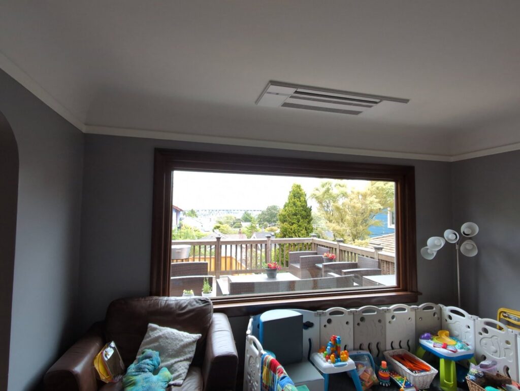 An indoor ceiling cassette HVAC unit installed in a living room by Progressive Comfort Solutions in Seattle, WA.