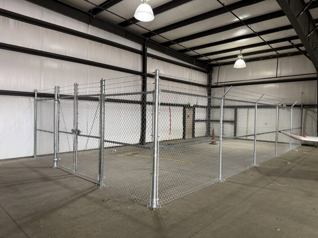 An indoor chain-link fence enclosure with barbed wire installed by Pueblo Fence Co in Pueblo West, CO.