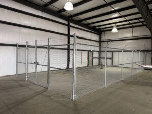 An indoor chain-link fence enclosure with barbed wire installed by Pueblo Fence Co in Pueblo West, CO.