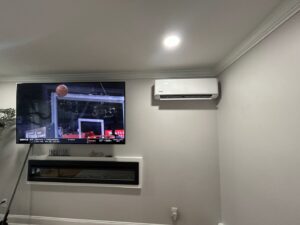 An indoor ductless mini-split unit installed on a wall above a television by Express Home Services LLC in Las Vegas, NV