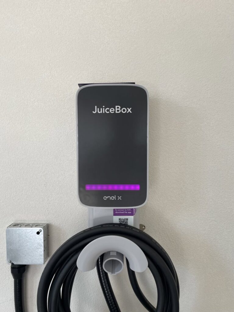 An indoor JuiceBox EV charger with coiled cable and electrical box installed by Delatour Electric in Portland, OR.