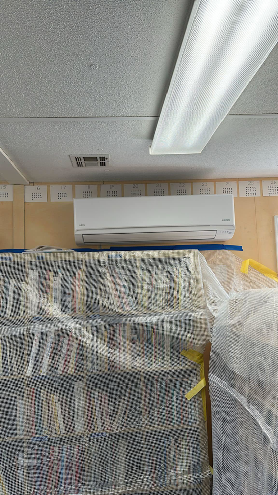 An indoor Fujitsu mini-split unit installed above bookshelves, showing an HVAC job by R&R Climate Systems in Newark, NJ