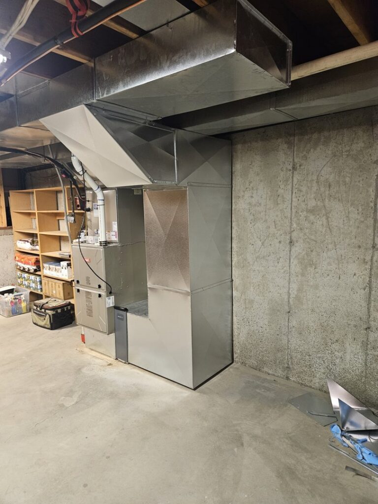 An indoor furnace and air handler unit with ductwork installed in a basement by ABC Mechanical Inc in Lawrenceville, GA.