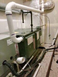 An indoor furnace and air handler unit with ductwork and PVC piping installed by Bean'z Heating and Cooling in Chicago, IL.