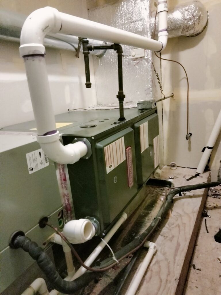 An indoor furnace and air handler unit with ductwork and PVC piping installed by Bean'z Heating and Cooling in Chicago, IL.