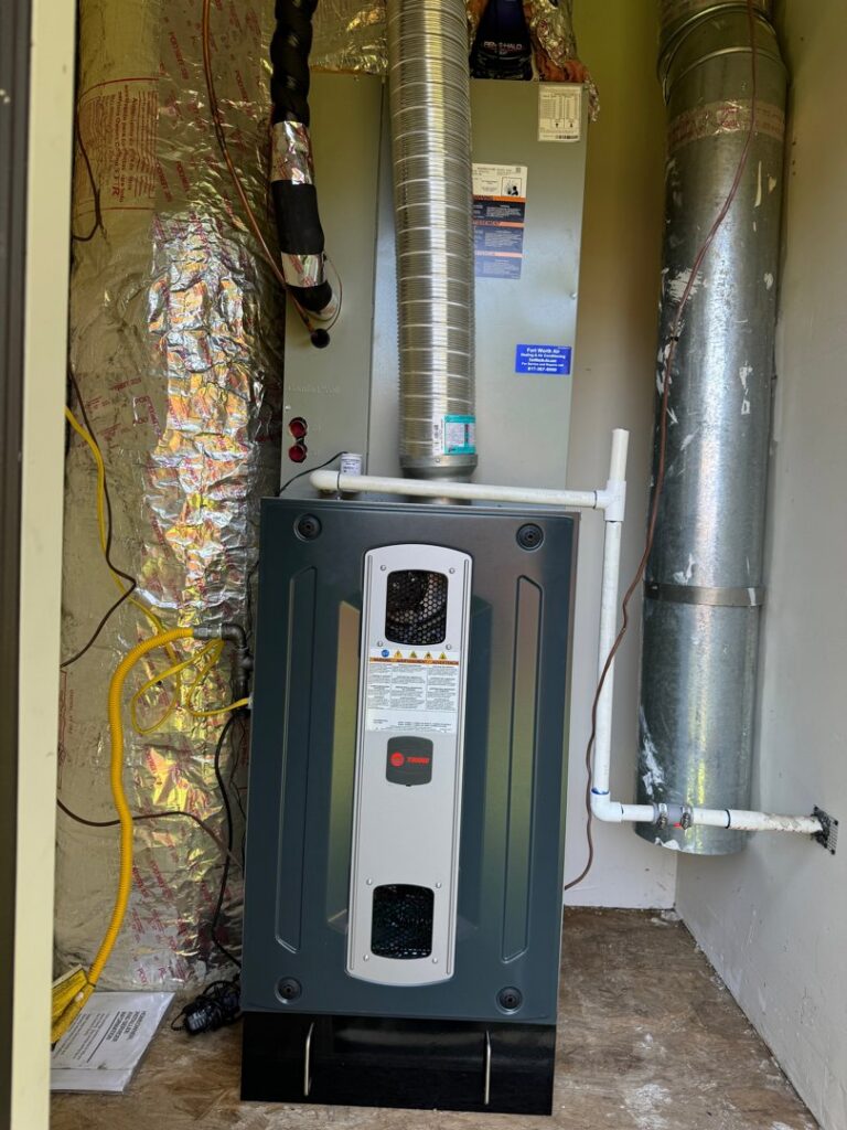 An indoor furnace and air handler unit with ductwork installed in a utility closet by Fort Worth Air Conditioning Co. Inc. in Fort Worth, TX.
