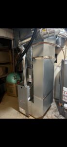An indoor furnace and air handler unit with ductwork and piping, representing an HVAC installation or service by Holzer Heating And Cooling in Savage, MN