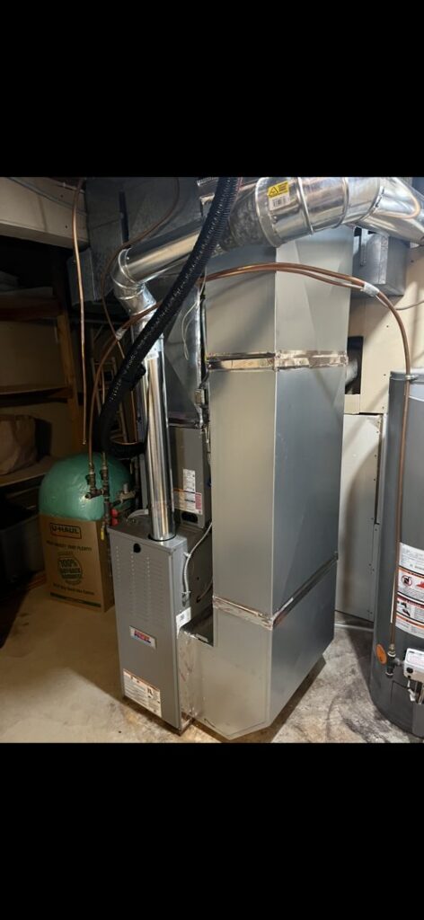 An indoor furnace and air handler unit with ductwork and piping, representing an HVAC installation or service by Holzer Heating And Cooling in Savage, MN