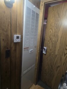 An indoor furnace and air handler unit with a thermostat on the wall, serviced by McElroy Service Experts in Grand Island, NE.