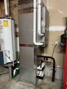 An indoor furnace and air handler unit installed next to a water heater, a service provided by McTeer's Heating & Cooling in Salisbury, MD.