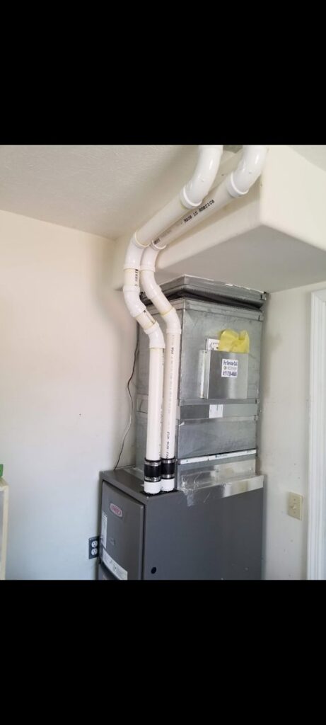 An indoor furnace and air handler unit with PVC venting installed by ESR Heating, Cooling and Refrigeration in Raymore, MO.