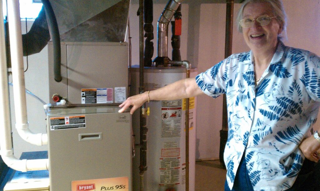 A man pointing to a newly installed indoor furnace and water heater by Sullivan Heating & Cooling in Depew, NY