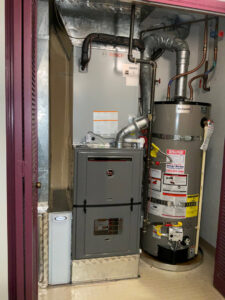 An indoor furnace and water heater system installed in a utility closet by Gresham Heating and Air Conditioning in Wood Village, OR.