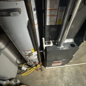 An indoor furnace unit next to a water heater, showing HVAC and plumbing work by Lopez Mechanical HVAC in Kansas City, MO.