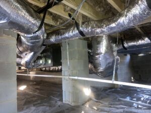 An indoor HVAC air handler unit with ductwork installed in a crawl space by Oakes AC Services, LLC in Louisburg, NC