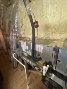 An indoor HVAC air handler unit with connected ductwork, showing a professional installation by Heads Heating & Air Conditioning in Theodore, AL.