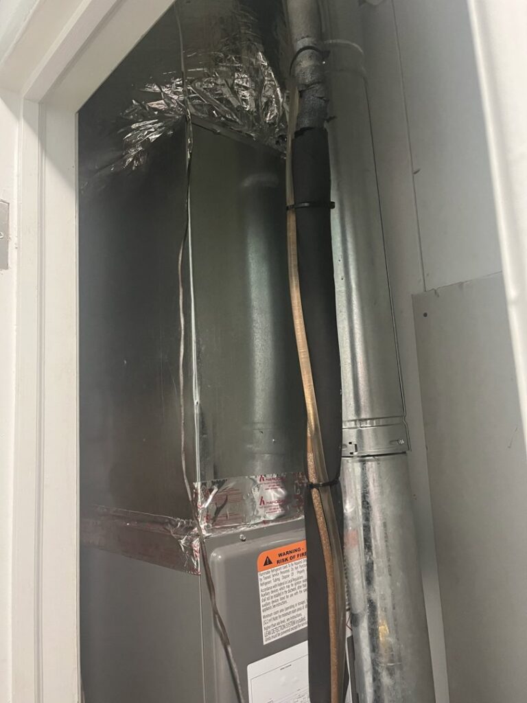 An indoor HVAC furnace and air handler unit with ductwork installed in a closet by Hendrix Heating & Air in Newport News, VA.