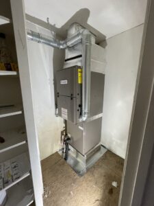 A compact indoor HVAC furnace and air handler unit installed in a utility closet by Coastal Breeze Heating-Cooling-Plumbing in Hampton, VA.