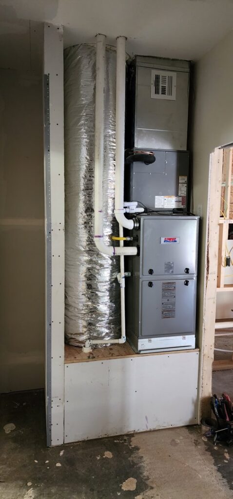 An indoor HVAC furnace and air handler unit with ductwork and piping installed by Fusion Heat and Air in Fort Smith, AR.