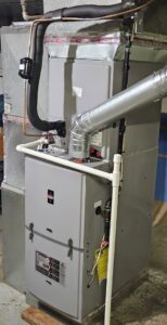 An indoor HVAC furnace system with connected ductwork and refrigerant lines, serviced by Astron Services LLC in Wichita, KS.