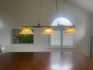 A newly installed indoor light fixture hanging over a dining table by River Electric, LLC in Greenville, SC.
