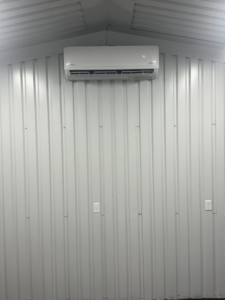 An indoor mini-split air handler unit installed on a white corrugated wall by HD Precision Works in Iota, LA.