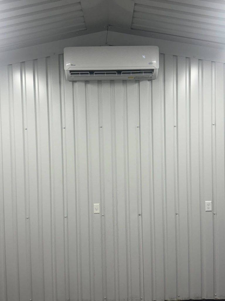 An indoor mini-split air handler unit installed on a white corrugated wall by HD Precision Works in Iota, LA.